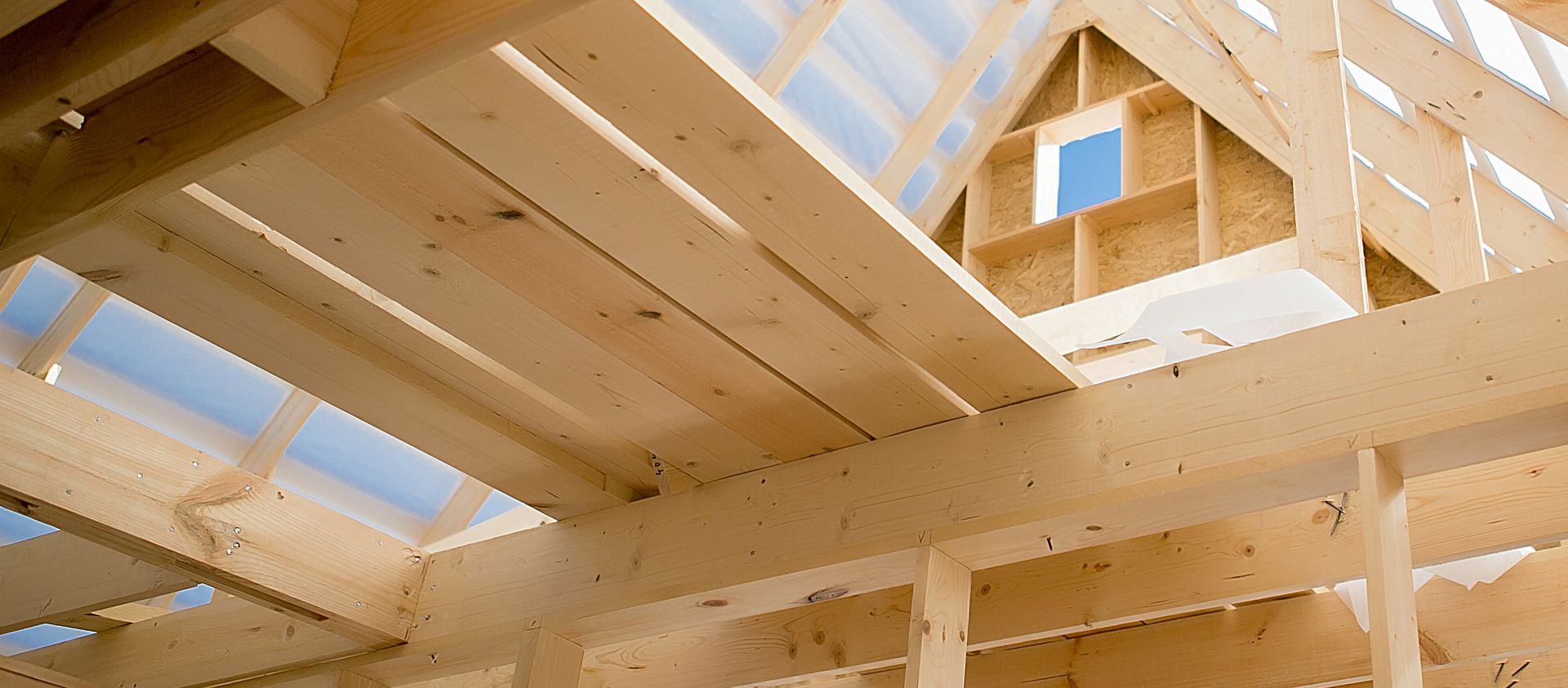 Holzkonstruktion eines Dachstuhls im Rohbau mit sichtbaren Balken und unvollständiger Isolierung